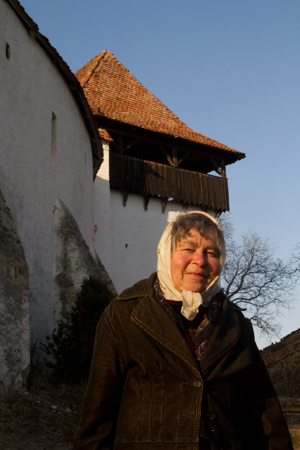Una anciana guía frente a uno de los muros de la iglesia fortificada de Viscri