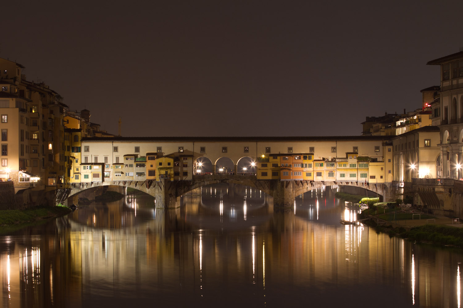 Vista nocturna del Ponte Vecchio con el río Arno corriendo a sus pies