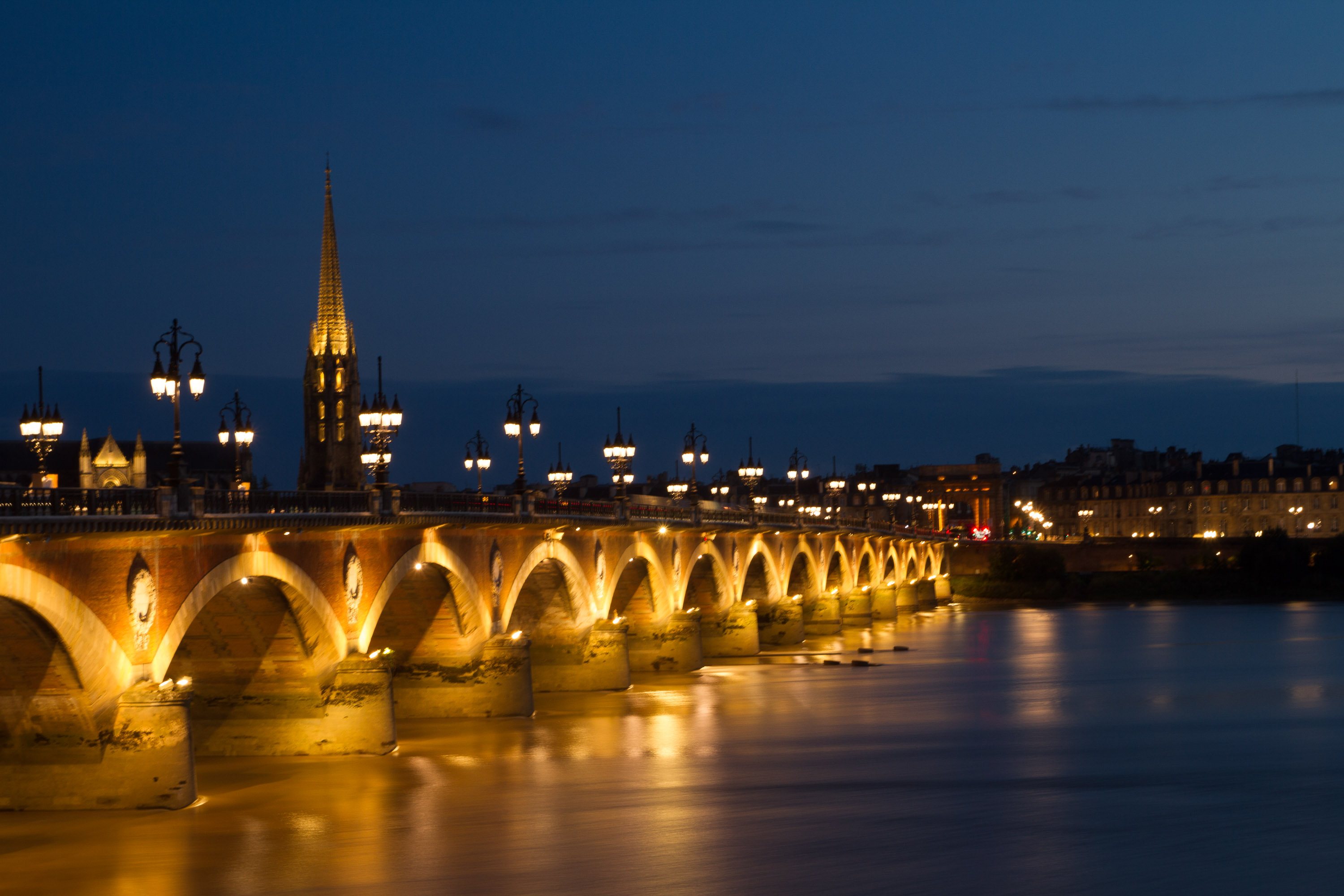 Vista nocturna del puente de piedra y la Basílica de San Miguel, Burdeos, Francia